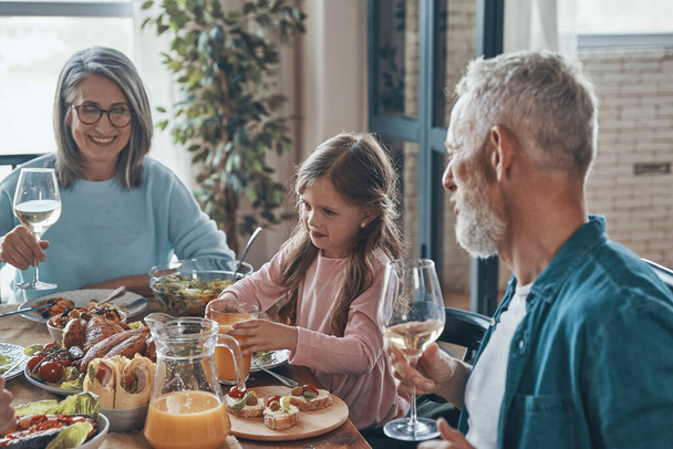 Happy multi-generation family communicating and smiling while having dinner together - Фото, изображение