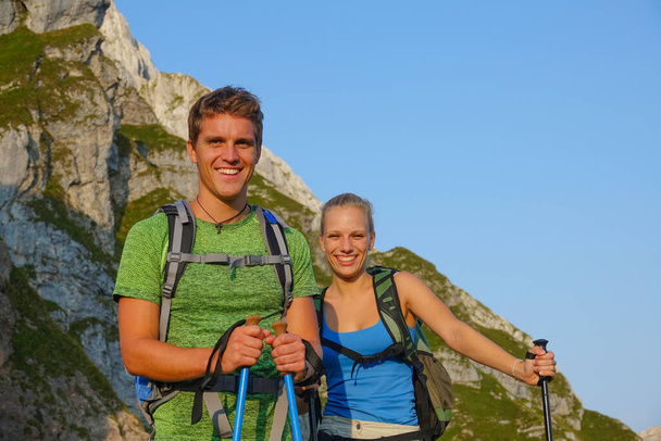 PORTRAIT: Cute hiker couple smiles after reaching the mountaintop in the Alps. - Foto, Imagen
