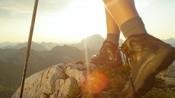 LENS FLARE: turista feminina vestindo botas de caminhada de couro atinge o cume. - Foto, Imagem