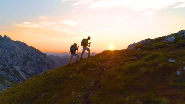 DRONE: coppia di escursionisti che si gode una gita serale nelle mozzafiato Alpi Giulie. - Foto, immagini