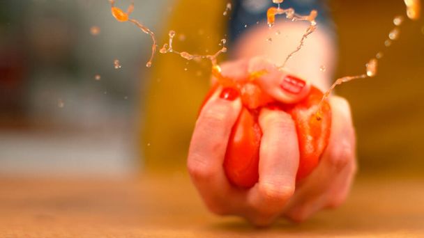 MACRO, DOF: Tomate orgânico explode na mão de uma chef feminina enquanto ela aperta. - Foto, Imagem