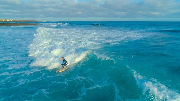 DRONE: Fit männliche Surfer surfen epische Barrel Wellen nahe felsigen Insel an einem sonnigen Tag - Foto, Bild
