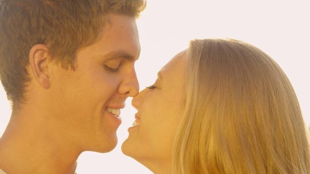 CLOSE UP: Яскраві сонячні промені світяться на людину, даруючи своїй дівчині ескімоський поцілунок
. - Фото, зображення