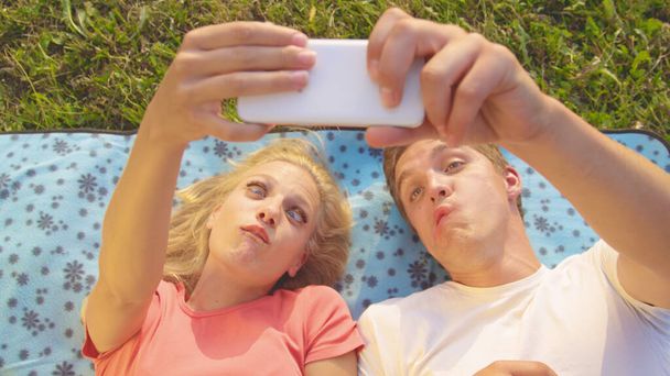 ZAMKNIJ SIĘ: podekscytowana młoda kobieta i mężczyzna robi śmieszne miny i robi selfie. - Zdjęcie, obraz