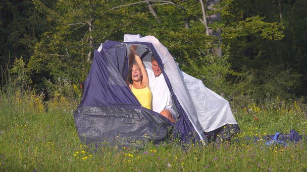 Happy Caucasian couple having fun preparing their tent during camping adventure - Foto, Imagen