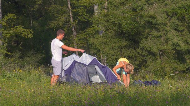 アクティブな夏休みの間に一緒にテントを設置する観光カップル. - 写真・画像