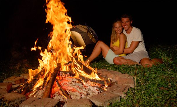 CLOSE UP: Beautiful girl cuddling with her boyfriend by the warm campfire. - Foto, Bild