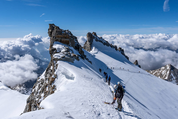 View from the summit of Gran Paradiso in 4061m above sea level, the highest mountain that is completely in Italy. Clouds in the valley are below, blue - Zdjęcie, obraz