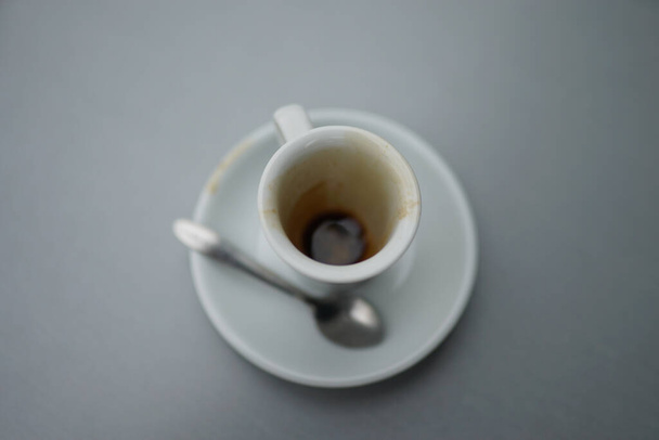 A top view of a dirty coffee cup with a saucer and spoon - Foto, afbeelding