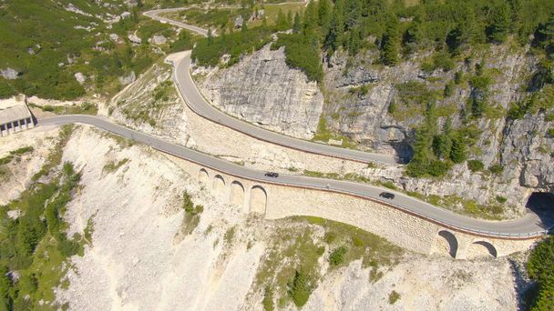 AERIAL: Carros esportivos e motocicletas dirigindo em um viaduto vazio em Alpes italianos. - Foto, Imagem
