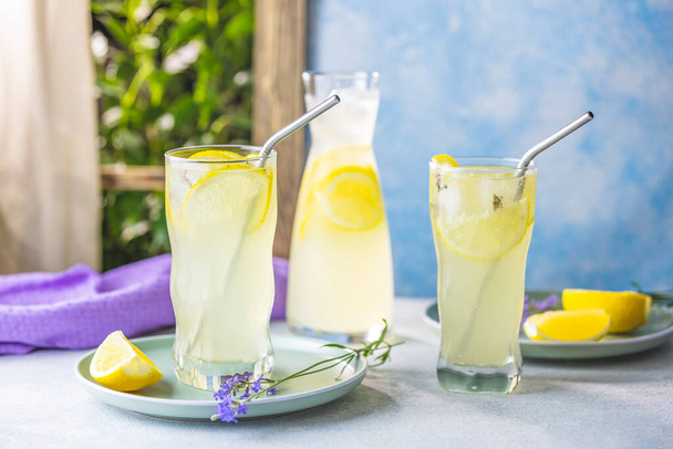 Szemüveg levendula limonádé kocka jég levendula virágok az asztalon ablak közelében a nyári napsütésben. - Fotó, kép