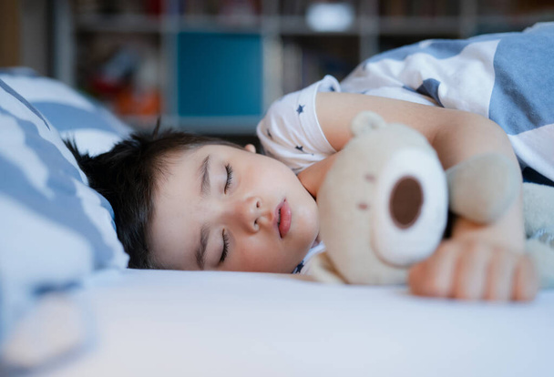 Leuke jongen slapen op bed met ochtendlicht, Lovely Child krijgen diepe slaap tijdens het nemen van een dutje, Kid ontspannen en gelukkig tijdens de nacht, Goede slaap is belangrijk voor het lichamelijke en geestelijke welzijn van het kind - Foto, afbeelding