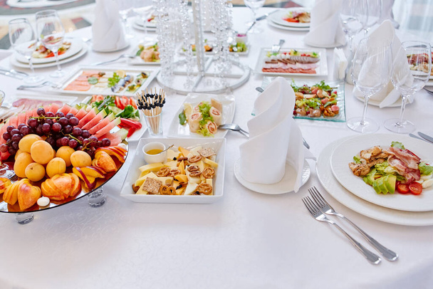 Beautifully decorated catering banquet table with different food snacks and appetizers , fresh fruits on corporate party event or wedding celebration - Φωτογραφία, εικόνα