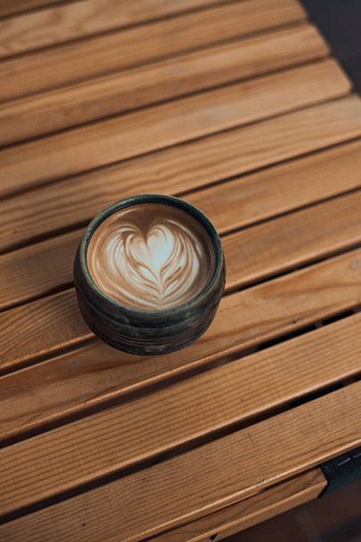 Selective focus cup of hot latte art coffee on wooden table,focus at white foam - Фото, зображення