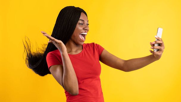 Iloinen Afrikkalainen nainen Älypuhelimen käyttäminen Selfie keltaisella taustalla - Valokuva, kuva