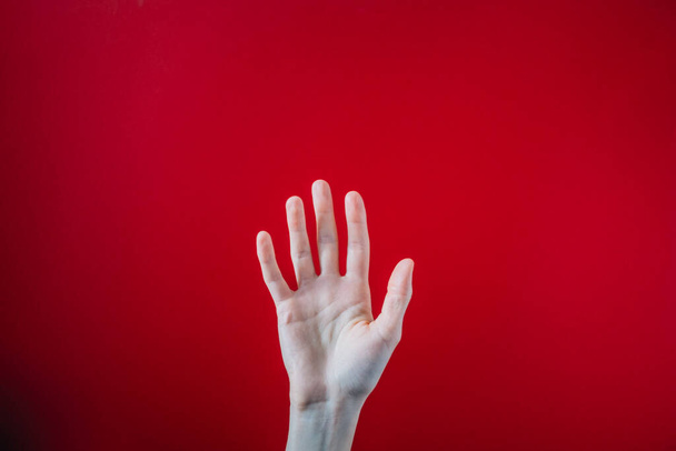 A closeup shot of a raised up hand on a red background - 写真・画像