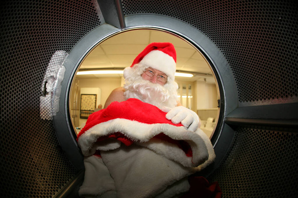 Санта Клаус. Рождество. Санта Клаус стирает свою одежду в прачечной перед Рождеством. Сосредоточься на одежде Санты. Санта Клаус стирает свою одежду в прачечной перед Рождеством. Санте нужна чистая одежда. Счастливого Рождества. Счастливые праздники.  - Фото, изображение