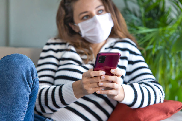 Worried young woman with protective mask is reading news on phon - Foto, Bild