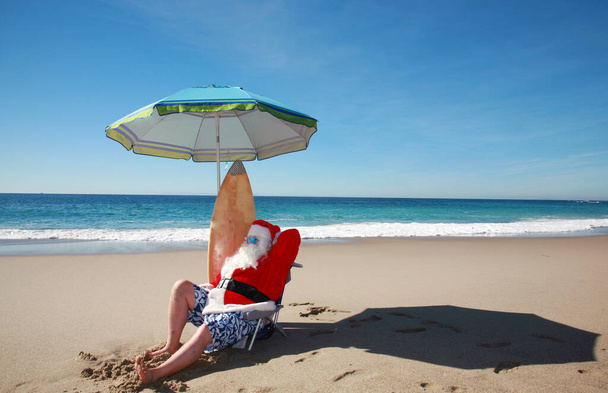 Navidad. Santa Claus disfruta de un día en la playa el día después de Navidad. Papá Noel se va de vacaciones. Vacaciones en Santa Claus Beach. Santa Claus se relaja en la playa bajo el sol. Santa Claus disfruta de unas vacaciones bien ganadas después de Navidad. Ho Ho Ho - Foto, Imagen