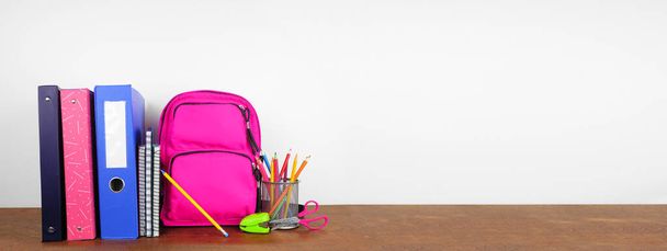 School binders and supplies on a wood shelf against a white wall banner background. Back to school concept. Copy space. - Photo, Image