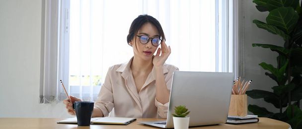 Mladá podnikatelka v brýlích pracuje na notebooku v kanceláři. - Fotografie, Obrázek