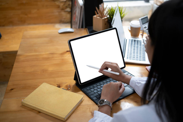 Over schouder uitzicht van jonge vrouw ontwerper houden stylus schrijven op het scherm van digitale tablet. - Foto, afbeelding