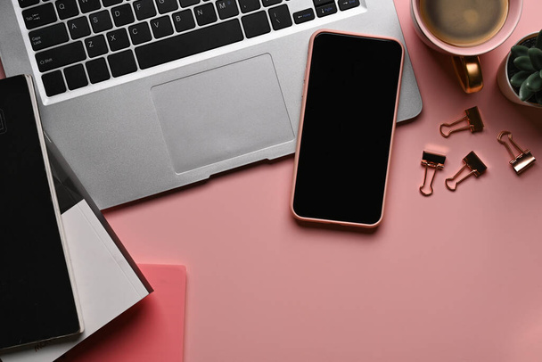Scrivania per ufficio. Posto di lavoro femminile con smart phone, computer portatile e accessori su sfondo rosa pastello. - Foto, immagini