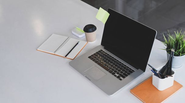 Computer laptop, notebook, koffiebeker en plant op wit bureau. - Foto, afbeelding