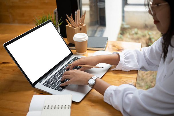 Przycięte zdjęcie bizneswoman w okularach pracujących z laptopem komputerowym w biurze. - Zdjęcie, obraz