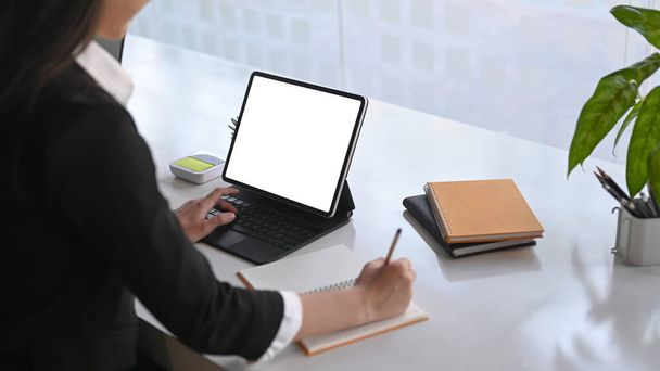 Donna d'affari che scrive informazioni su notebook e lavora con tablet per computer in ufficio. - Foto, immagini