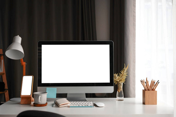 Mock up computador e telefone inteligente com tela branca na mesa branca no confortável escritório em casa. - Foto, Imagem