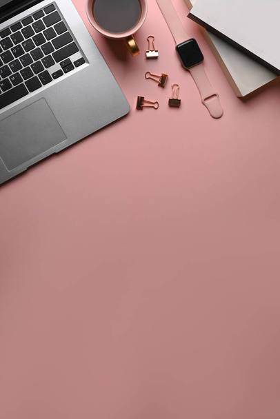 Vista superior del lugar de trabajo femenino con computadora portátil, reloj inteligente, taza de café, cuaderno y espacio de copia sobre fondo rosa. - Foto, Imagen