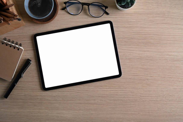 Vue aérienne du lieu de travail design avec tablette numérique, tasse à café, ordinateur portable et lunettes sur un bureau en bois. - Photo, image