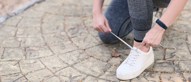 Close up view of sporty woman tying shoelace on the street. - Zdjęcie, obraz
