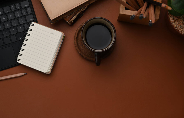 Vista superior del espacio de trabajo vintage con cuaderno vacío, taza de café, teclado y espacio de copia de cuero marrón. - Foto, imagen