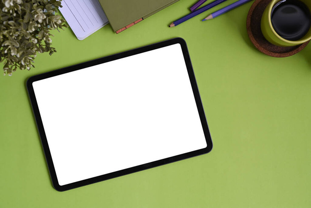 緑の背景に空白の画面、コーヒーカップや文房具とデジタルタブレットをモックアップのトップビュー. - 写真・画像