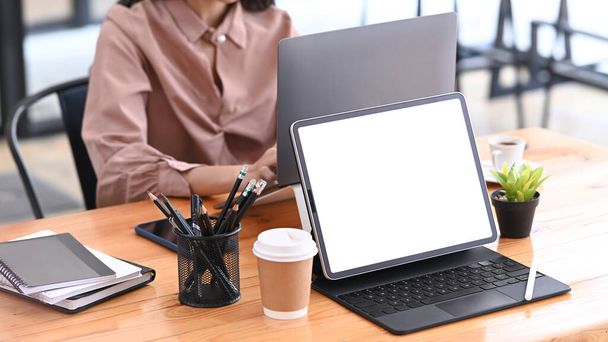 Tablica komputerowa z pustym ekranem na drewnianym stole w biurze kreatywnym. - Zdjęcie, obraz