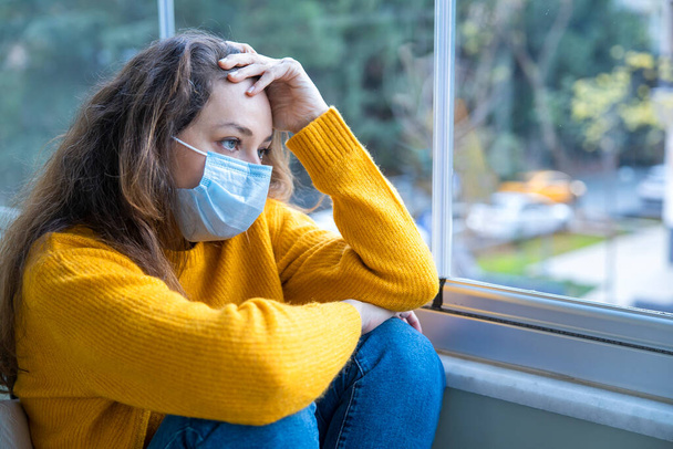 Young woman in medical mask staying at home under quarantin - Valokuva, kuva