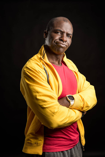 Πορτρέτο ενός μαύρου άνδρα με σταυρωμένα χέρια που στέκεται κοιτάζοντας την κάμερα - Φωτογραφία, εικόνα