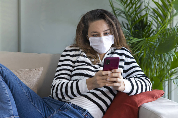 Worried young woman with protective mask is reading news on phon - Foto, Bild