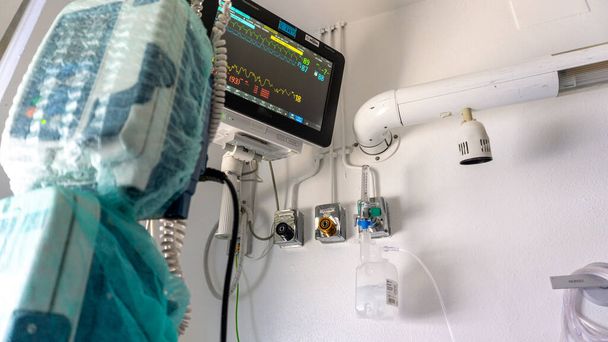 screen that shows the parameters of a person who is admitted to the ICU and with the medicine dispensers and the gas intakes for breathing - Fotó, kép
