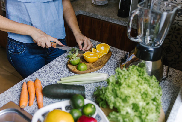 Latin Woman macht grünen Smoothie oder Detox-Saft in der Küche zu Hause in gesunde Ernährung Konzept in Mexiko - Foto, Bild