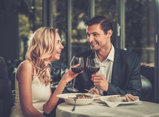 fröhliches Paar in einem Restaurant mit einem Glas Rotwein - Foto, Bild