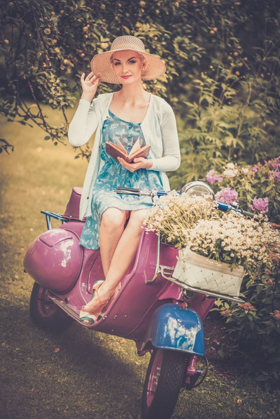 Belle femme blonde assise sur un rouleau rétro avec un livre
 - Photo, image