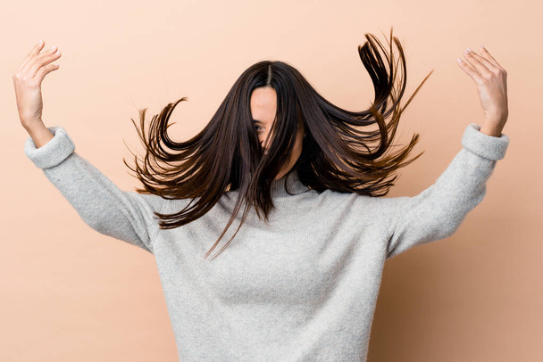 Young indian woman moving her hair isolated on beige background - Foto, afbeelding