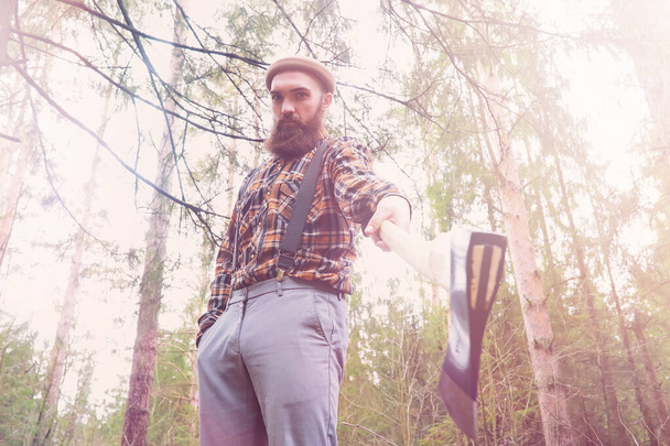 A bearded lumberjack with a large ax examines the tree before felling - Valokuva, kuva
