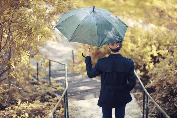 Parque de otoño en tiempo lluvioso y un joven con un paraguas - Foto, Imagen