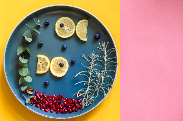 pesci da fette di limone nuotare su piatto con piante verdi, copiare spazio isolato su sfondo rosa e giallo - Foto, immagini