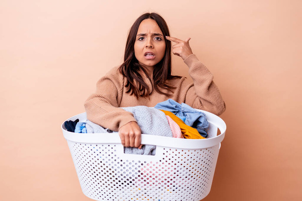 Young mixed race woman holding a laundry isolated showing a disappointment gesture with forefinger. - Foto, Bild
