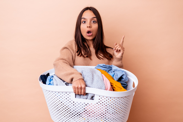 Young mixed race woman holding a laundry isolated having some great idea, concept of creativity. - Valokuva, kuva